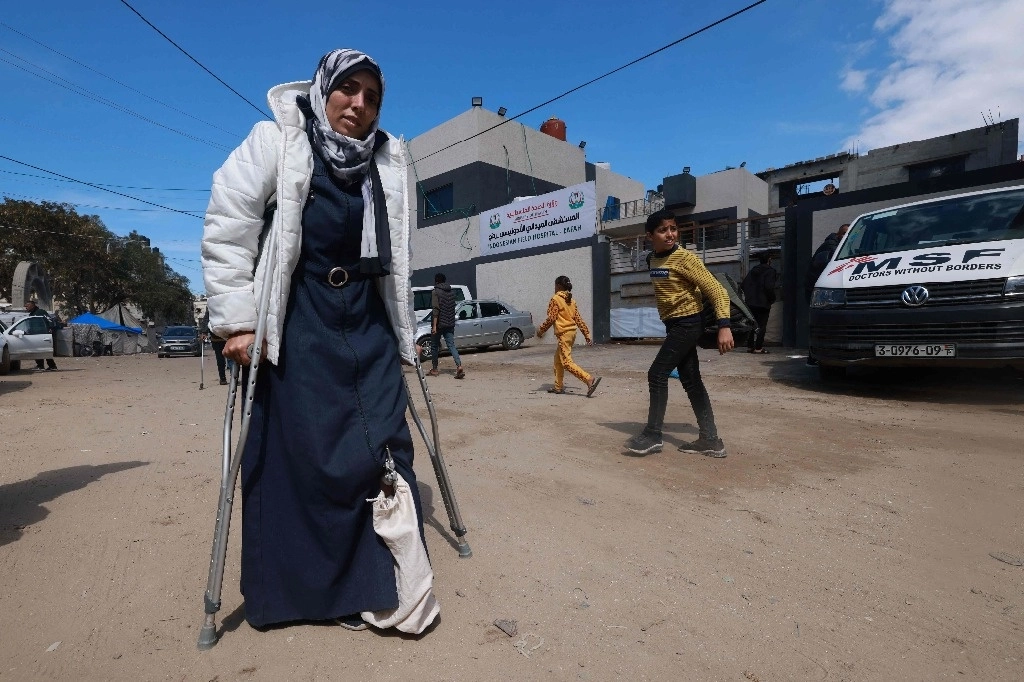 La palestina Maha Abo Naja usa sus muletas para caminar afuera de una clínica establecida por Médicos Sin Fronteras (MSF) dentro del Hospital de Campaña Indonesio de Rafá en Rafá, en el sur de la Franja de Gaza, donde está siendo tratada por las heridas sufridas durante el bombardeo israelí, el 7 de marzo de 2024. Foto Afp