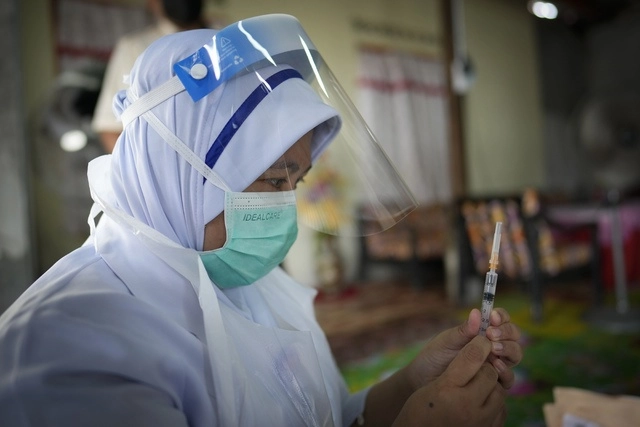 Una enfermera se prepara para aplicar una vacuna de Pfizer contra el Covid-19 a una mujer mayor en una casa rural en Malasia. Foto Ap