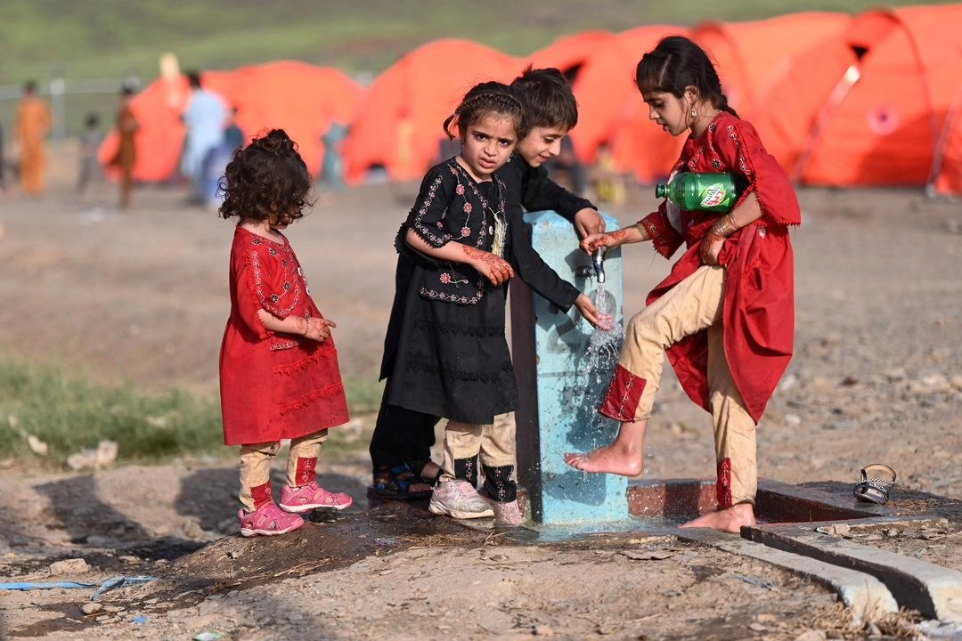 Niños afganos se lavan los pies cerca de la frontera entre Afganistán y Pakistán en Torkham, en la provincia de Nangarhar, el 20 de abril de 2025.