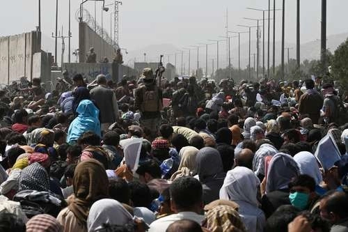 Una multitud de afganos se agolpa en el camino hacia el hangar militar de esa terminal aérea. Foto Afp

