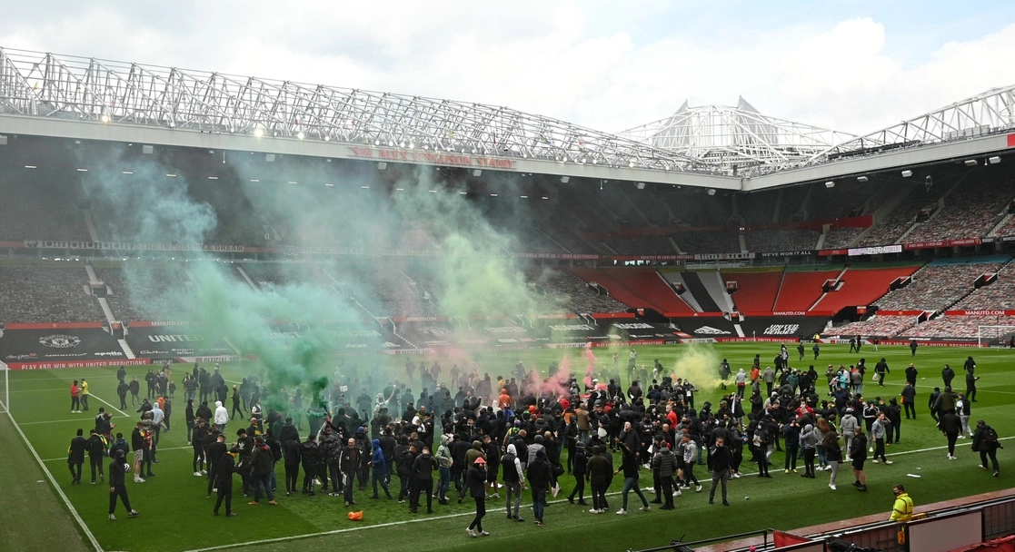 Hinchas invadieron ayer la cancha del estadio del Manchester United, donde encendieron bengalas y treparon a las porterías y a las gradas mientras entonaban consignas contra los propietarios del plantel. Foto Afp
