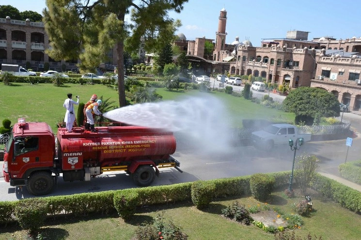 Trabajadores de rescate rocían la solución de un camión de agua para desinfectar un área como medida preventiva contra el coronavirus COVID-19, en Peshawar. Foto AFP