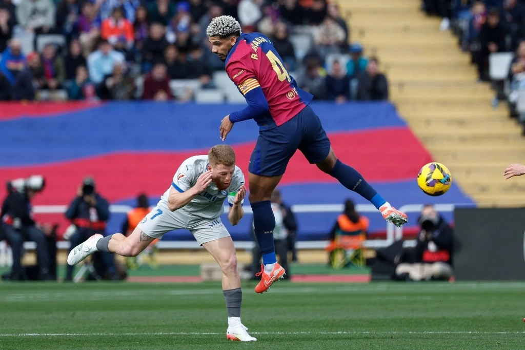 Carlos Vicente del Alavés, izquierda, y Ronald Araújo del Barcelona desafían el balón durante un partido de futbol de la Liga española en el Estadio Olímpico Lluís Companys en España, el 2 de febrero de 2025. Foto Ap