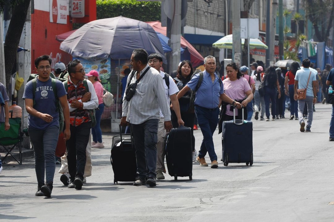 Pasajeros afectados por la marcha de integrantes de la CNTE buscan llegar a las instalaciones del AICM, donde profesores se reúnen para exigir un aumento salarial, la abrogación de la Ley del Issste de 2007 y la reforma educativa, en la Ciudad de México, el 23 de mayo de 2025. 