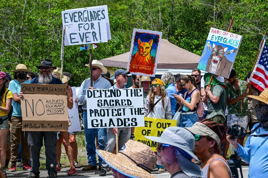 Manifestantes sostienen pancartas mientras protestan contra la construcción de un centro de detención para inmigrantes, denominado "Alcatraz de los Caimanes", en los Everglades, cerca de Ochopee, Florida, el 28 de junio de 2025. Foto 