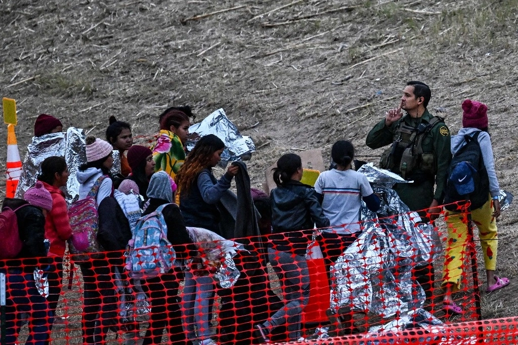 Migrantes esperan a ser procesados por la Patrulla Fronteriza en el cruce de Eagle Pass, en Texas. Foto Afp.