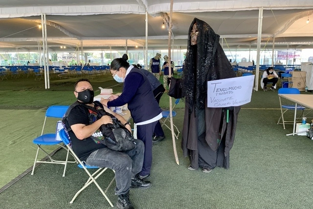 Una persona disfrazada de la Parca (der) acudió al módulo de vacunación Xochimilco a recibir la segunda dosis del biológico contra Covid-19. Foto Marco Peláez 