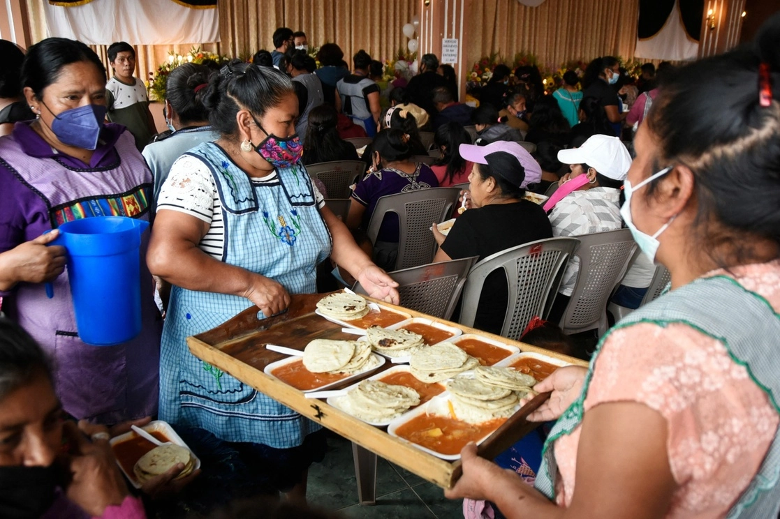 Mujeres entregan comida durante un funeral en el municipio guatemalteco de Magdalena Milpas Altas. Foto Afp.