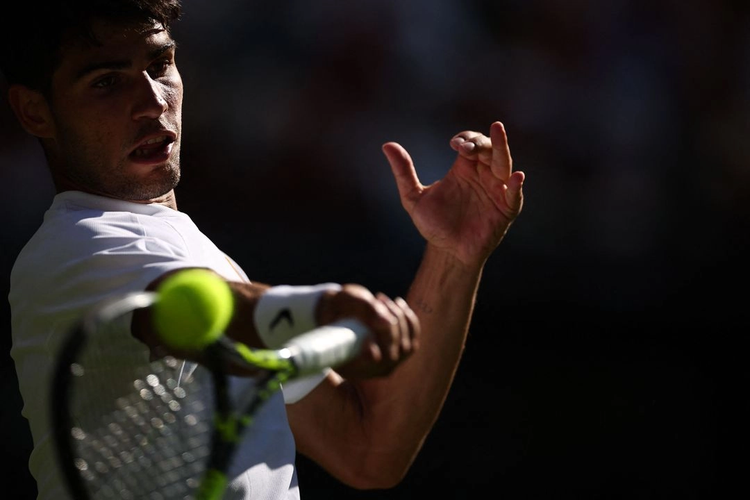 El español Carlos Alcaraz devuelve un golpe de derecha al italiano Fabio Fognini durante su partido de primera ronda de tenis individual masculino en el primer día del Campeonato de Wimbledon 2025 en el All England Lawn Tennis and Croquet Club en Wimbledon, al suroeste de Londres, el 30 de junio de 2025. Foto