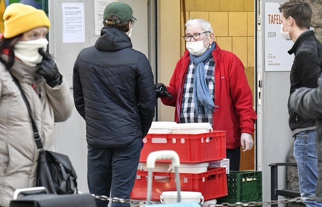 Un ayudante de un banco de comida controla la entrada con un cubrebocas en Essen, Alemania. Foto Ap 