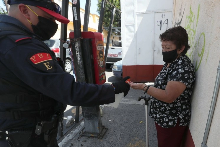 Policía capitalino ofrece gel antibacterial a peatona en la alcaldía Álvaro Obregón. Foto LA JORNADA/José Antonio López