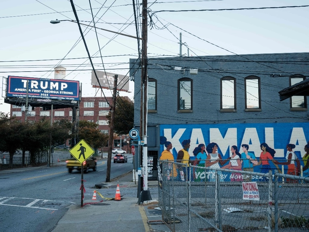 Grafitti en favor de Kamala Harris, candidata demócrata a la presidencia de EU junto a un anuncio electrónico del aspirante republicano, Donald Trump, en Atlanta, Georgia. Foto Afp