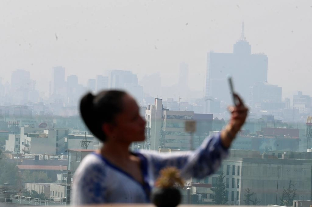 Una joven se toma una fotografía en la terraza del Hotel Fontan, desde la cual se puede observar la mala calidad del aire de la Ciudad de México, el 13 de noviembre de 2022. Foto Roberto García Ortiz
