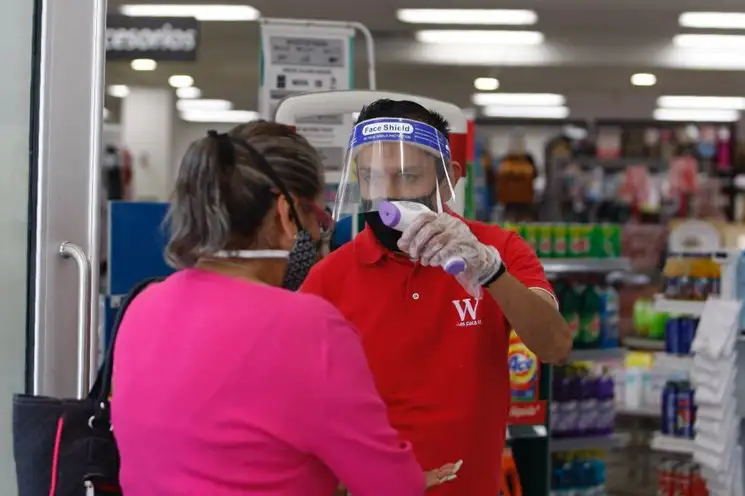 Un trabajador de un supermercado toma las medidas sanitarias necesarias para dejar entrar a los clientes, en Ciudad de México. Foto Roberto García Ortiz 