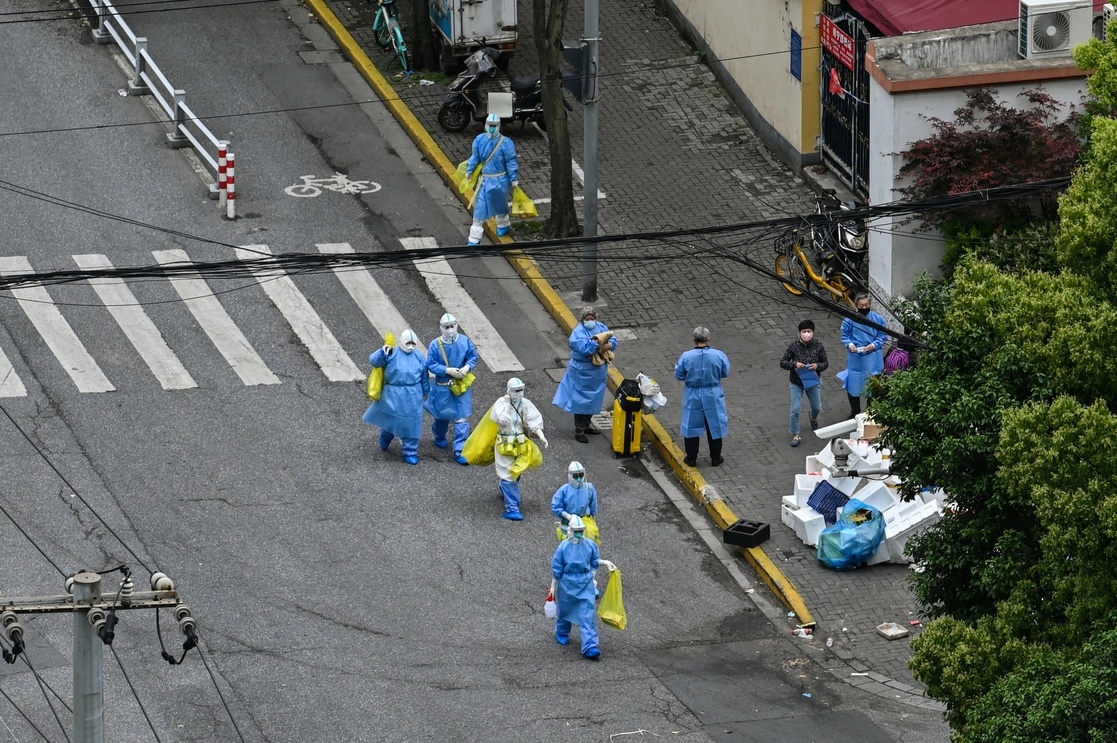 Trabajadores de la salud caminan por una calle de Shanghai, China, durante el confinamiento por la persistencia del covid-19, el 24 de abril de 2022. Foto Afp