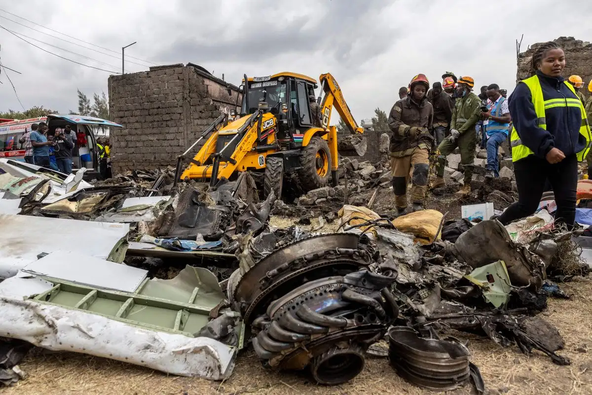Rescatistas caminan junto a los restos del accidente de un avión médico keniano en las afueras de Nairobi, el 7 de agosto de 2025. Foto