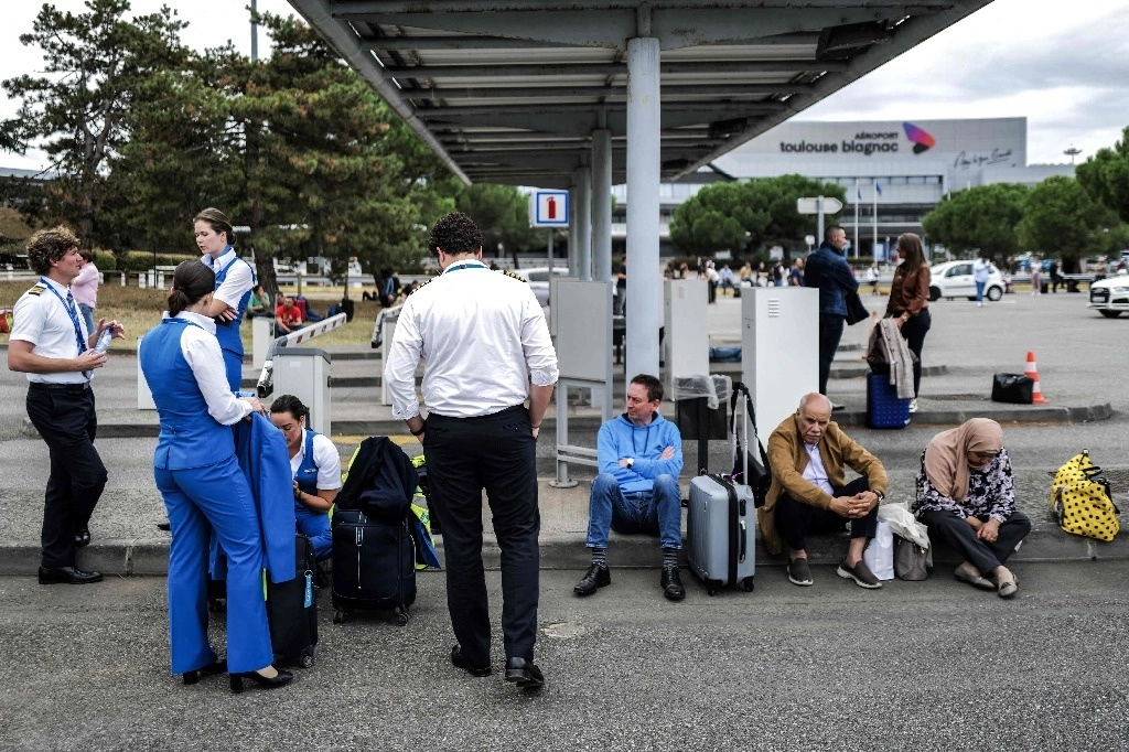 Pasajeros y trabajadores de aerolíneas esperan afuera del aeropuerto de Toulouse-Blagnac, al suroeste de Francia, tras su evacuación, el 18 de octubre de 2023. Foto Afp 