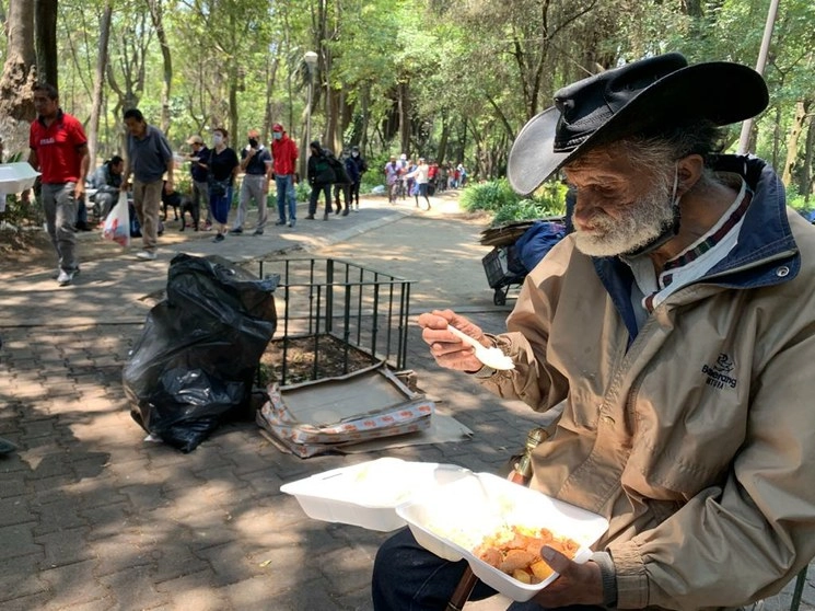 Un hombre come lo ofrecido por parte de un grupo de voluntarios que da alimentos a quien lo necesite durante la crisis económica debido al Covid-19, en el Jardín Ramón López Velarde, ubicado frente al Centro Médico Siglo XXI, en la CDMX. Foto José Antonio López 