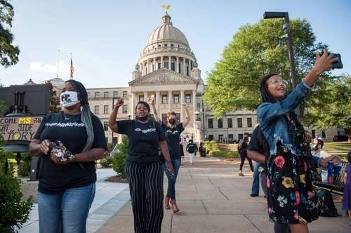 Manifestantes celebran el voto histórico de la legislatura de Misisipi para cambiar la bandera estatal que incluía un emblema de batalla confederado, adoptado después de la Guerra de Secesión. El nuevo diseño incluirá la frase En Dios confiamos. Foto Afp