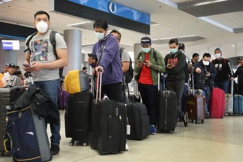 En medio del temor a contraer el nuevo coronavirus, pasajeros esperan en el mostrador de Qatar Airways para volver a su país y salir de Estados Unidos, en el Aeropuerto Internacional de Miami, Florida. Foto Afp