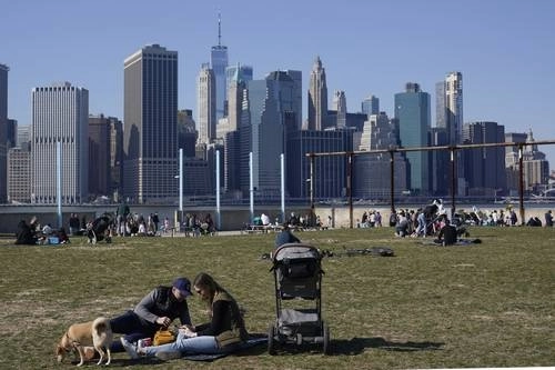 La gente disfruta del clima soleado y una vista del horizonte de Manhattan desde el puerto de Brooklyn, en Nueva York. El invierno finalmente se rindió y entregó a la ciudad al abrazo –a sana distancia– de la primavera, y con ello apenas se van descubriendo las señales de vida, después de uno de los peores inviernos en la historia de esta ciudad. Foto Ap