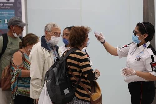 En el aeropuerto de la Ciudad de México, personal de seguridad registra la temperatura a pasajeros, como parte de la medidas de prevención contra el Covid-19. Foto María Luisa Severiano