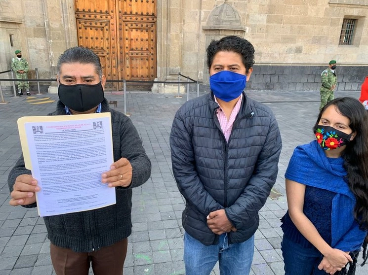 Integrantes de la Comisión Ejecutiva de la CNPA-MN muestran la resolución del CJF sobre el amparo a favor de pueblos indígenas para informar en sus lenguas maternas las políticas de salud contra Covid-19, frente al Palacio Nacional, en el Centro Histórico. Foto María Luisa Severiano