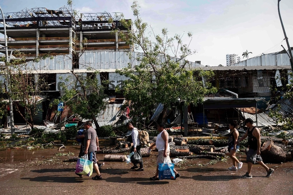 Habitantes de Acapulco caminan por un área dañada, tras el paso del huracán 'Otis'. Foto AFP
