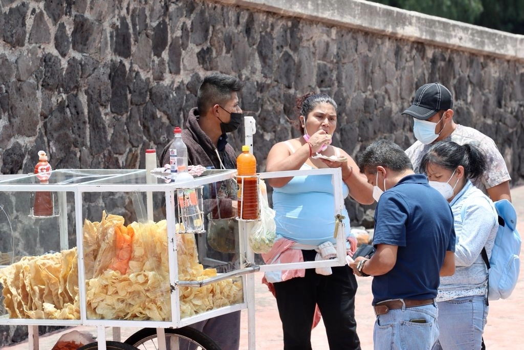 Un grupo de personas compra frituras a un vendedor ambulante, en el área circundante al Estadio Olímpico Universitario, Ciudad de México. Foto Roberto García Ortiz / Archivo

