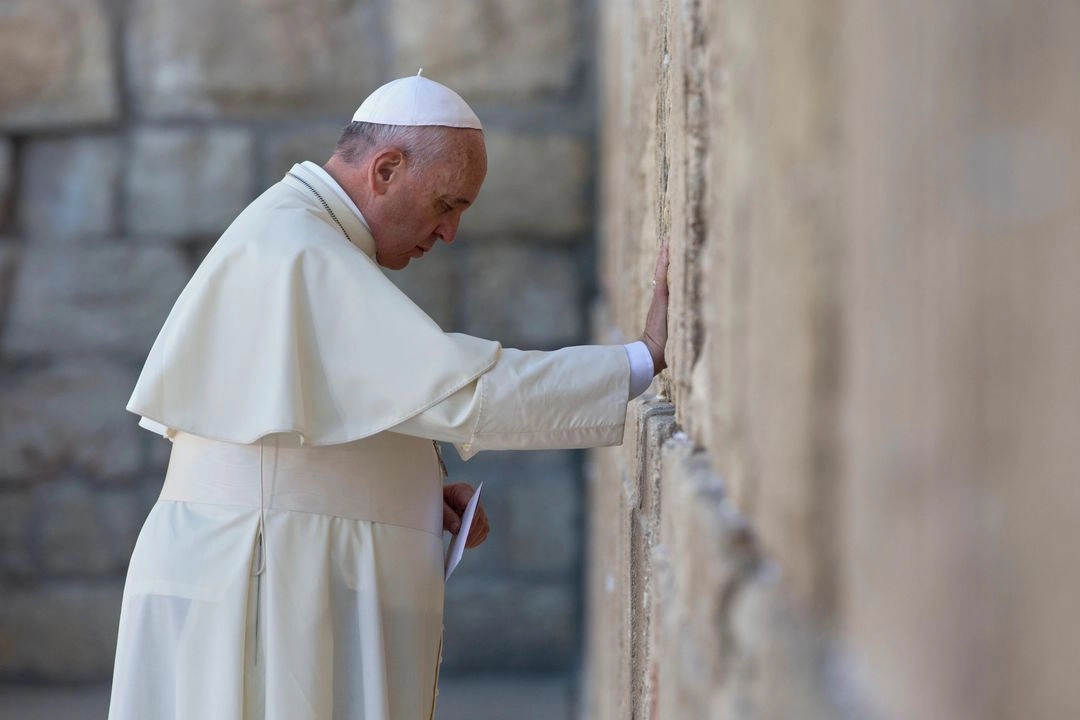 El Papa Francisco reza mientras sostiene un sobre antes de colocarlo en una de las grietas entre las piedras del Muro de las Lamentaciones, el lugar más sagrado donde los judíos pueden rezar, en la ciudad vieja de Jerusalén, Israel, el 26 de mayo de 2014.