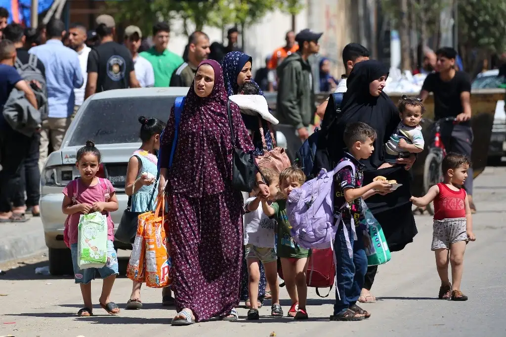 Mujeres y niños palestinos salen de Rafah, al sur de la franja de Gaza, con algunas de sus pertenencias. Foto Afp 