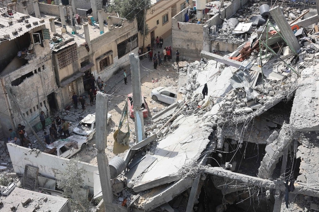 Personas inspeccionan un edificio dañado en un bombardeo israelí, en el vecindario de Al Daraj en Gaza. Foto Afp 