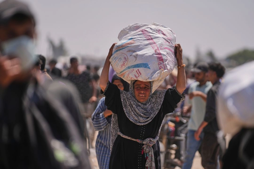 Una mujer palestina lleva una bolsa con alimentos y ayuda humanitaria entregada por la Fundación Humanitaria de Gaza, una organización respaldada por Estados Unidos, en Rafah, al sur de la Franja, el 11 de junio de 2025. Foto 