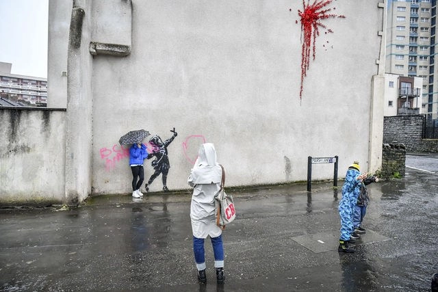 El arte callejero de Banksy suele llamar la atención, al agregar elementos oscuros a escenas que de otra manera serían alegres. Foto Ap
