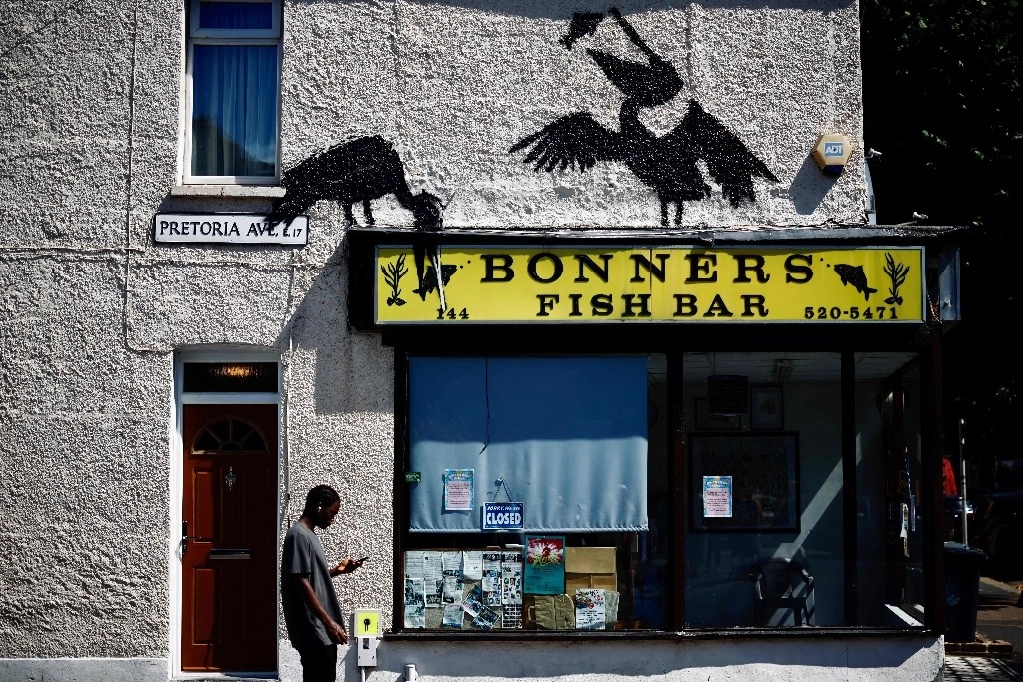 Un peatón pasa junto a la pinta más reciente de Banksy, en la pared de una tienda de comida en el noreste de Londres. Foto Afp