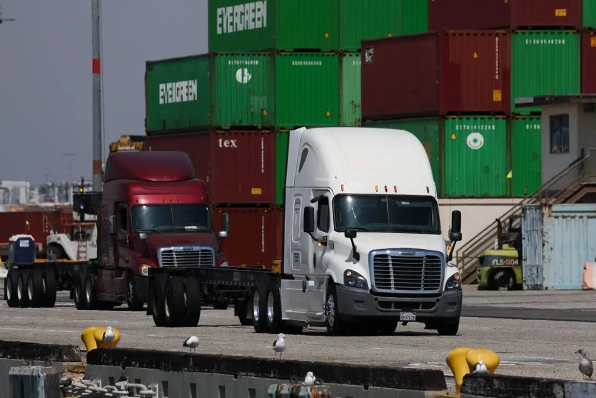 Camiones pasan junto a contenedores de carga en la terminal Evergreen del Puerto de Los Ángeles, California, el 13 de septiembre de 2025.