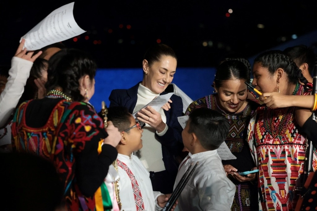 La presidenta Claudia Sheinbaum rodeada de personas que buscan una foto o platicar con ella en un acto en el Museo Nacional de Antropología. Foto Presidencia