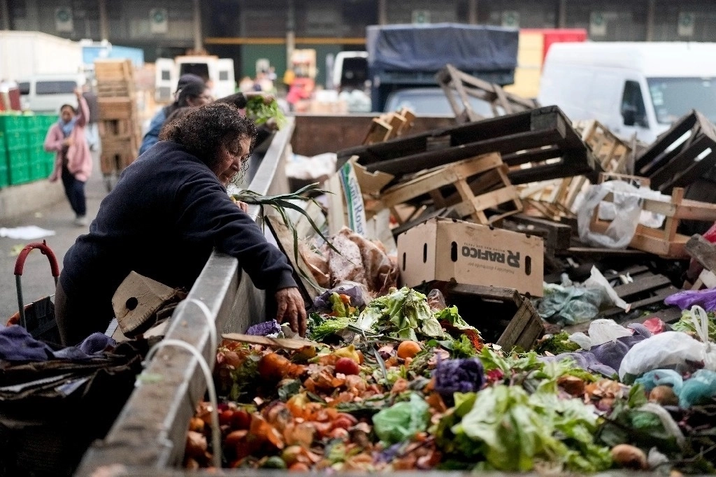 Una mujer busca en un contenedor de productos desechados afuera de un mercado en Buenos Aires, Argentina, el 1 de septiembre de 2023. Foto Ap