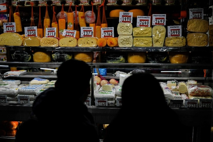 Una pareja revisa los precios en una tienda de quesos en el Mercado Central de Buenos Aires el 13 de junio de 2023. Foto Afp