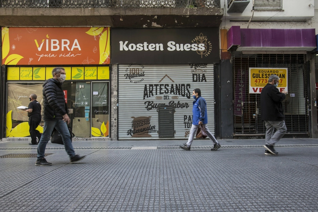 Personas caminan frente a locales comerciales cerrados de forma definitiva en la calle Florida, en la ciudad de Buenos Aires. Foto Xinhua