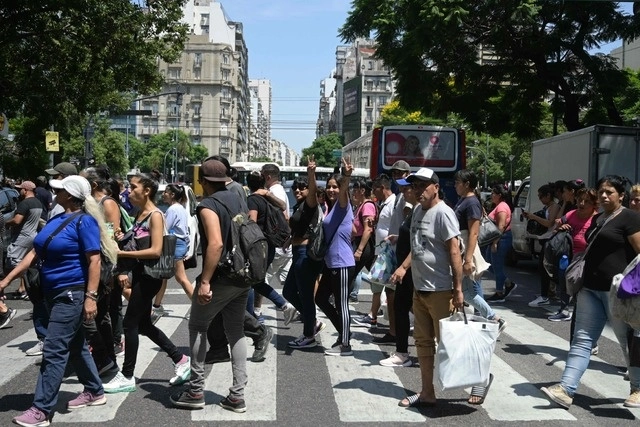 Personas y miembros de comedores sociales cruzan la Avenida Santa Fe después de participar en una protesta denominada "Línea del Hambre". Foto Afp