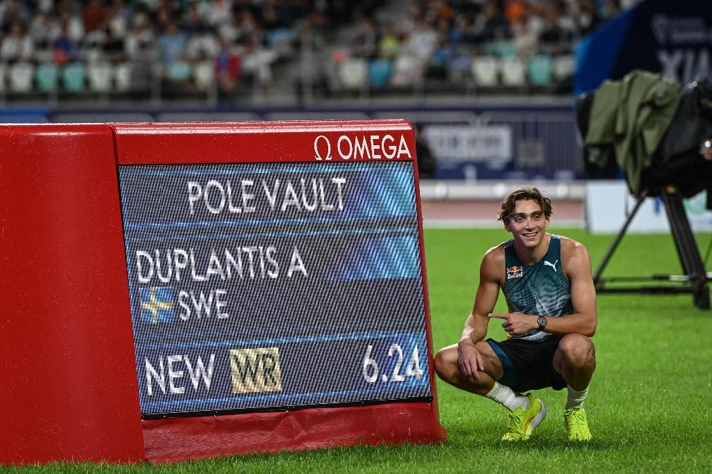Armand Duplantis posa junto al tablero con su marca de 6.24 metros, nuevo récord mundial de salto con garrocha. Foto Afp