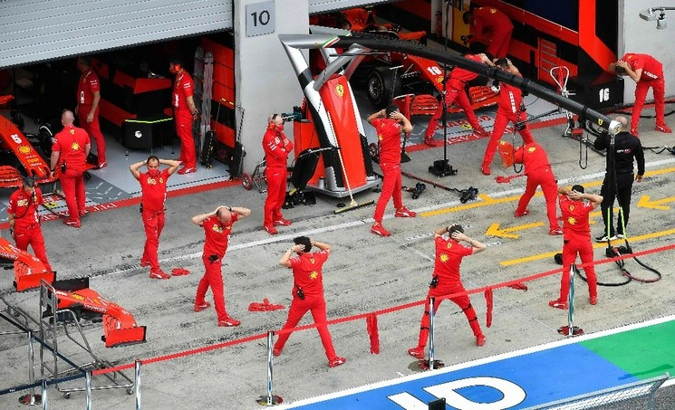 Los mecánicos de Ferrari realizan algunos ejercicios de calentamiento antes de la primera sesión de práctica en el Gran Premio de la Fórmula 1 de Austria. Foto Afp