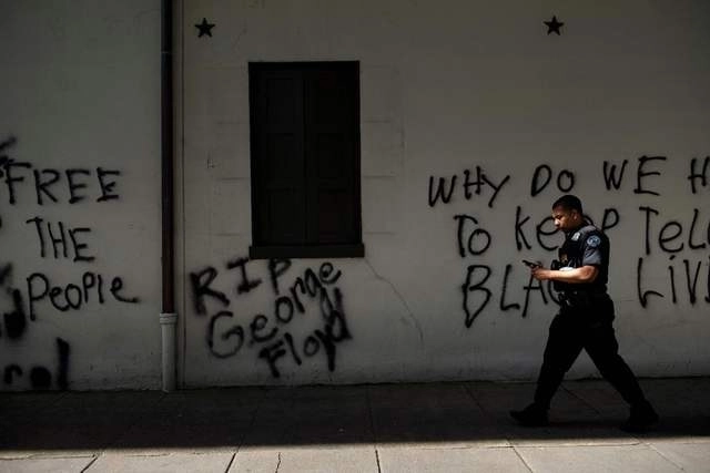 Un miembro del Servicio Secreto de EU pasa junto a un graffiti cerca de la Casa Blanca, tras una noche de protestas por la muerte de George Floyd. Foto Afp 