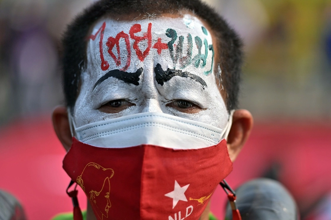 Un manifestante con la palabra "Birmania" escrita en la frente lleva una máscara facial del partido Liga Nacional para la Democracia (NLD), en protesta por el golpe militar de Myanmar. Foto Afp