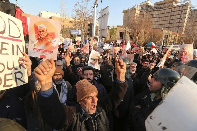 Manifestantes iraníes enarbolan retratos del asesinado comandante Qasem Soleimani, frente a la embajada británica en Teherán. Foto Afp 