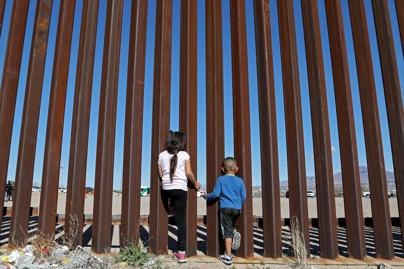 Dos niños miran a través de la valla fronteriza en Ciudad Juárez, mientras los agentes de la Patrulla Fronteriza de los Estados Unidos realizan un ejercicio de entrenamiento en Nuevo México, el 31 de enero de 2020. Foto Afp