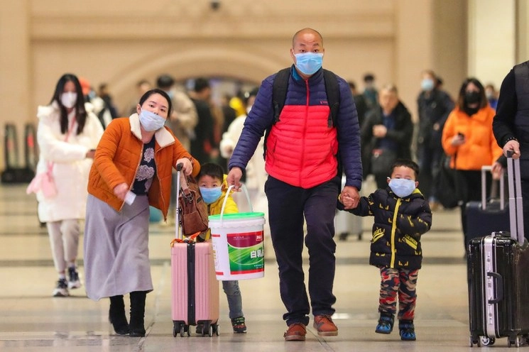 Turistas llevan cubrebocas para cubrirse y caminan con su equipaje en la estación del tren de Hankou en Wuhan, en la provincia meridional china de Hubei. Foto Ap