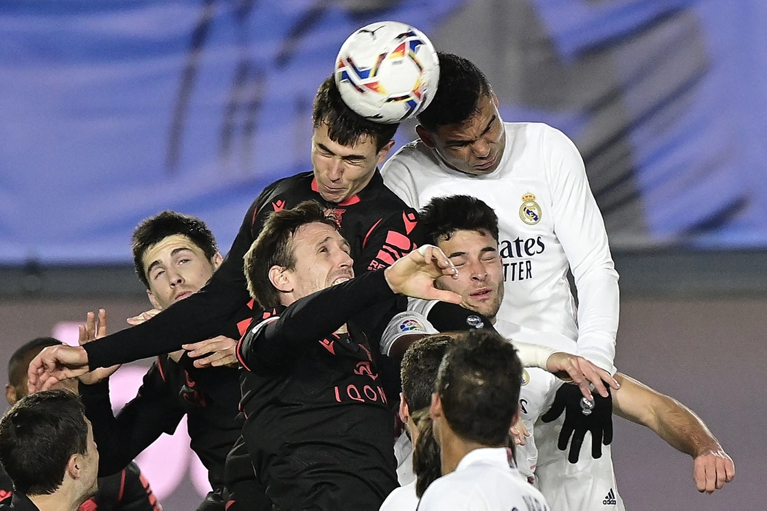 El brasileño Casemiro (de blanco) del Real Madrid disputa el balón con el español  Martin Zubimendi, de la Real Sociedad, en el estadio Alfredo Di Stéfano, en la periferia de la capital española, el 1 de marzo de 2021. Foto Afp