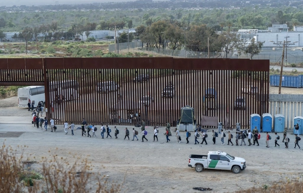 INGRESAN A EU POR TIJUANA. Decenas de migrantes cruzaron ayer a Estados Unidos por el tramo del muro fronterizo de la colonia Alemán, en Tijuana, Baja California, donde fueron revisados por elementos de la Patrulla Fronteriza. Según autoridades estadunidenses, debido al decreto del presidente Joe Biden que entró en vigor el miércoles pasado, estas personas están sujetas a la nueva normatividad, por lo que ya no son elegibles para el asilo, con algunas excepciones como menores no acompañados o personas enfermas. Foto Omar Martínez / 'La Jornada BC', con información de Mireya Cuéllar, corresponsal